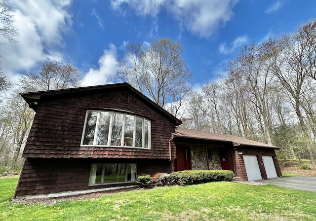 view of front of home featuring an attached garage, driveway, and a front yard