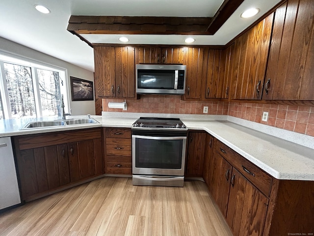 kitchen featuring light countertops, stainless steel appliances, a sink, and light wood-style floors