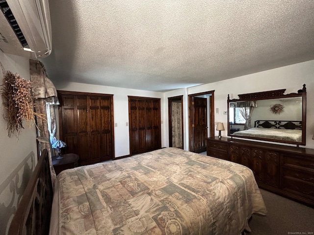 carpeted bedroom with a textured ceiling and multiple closets