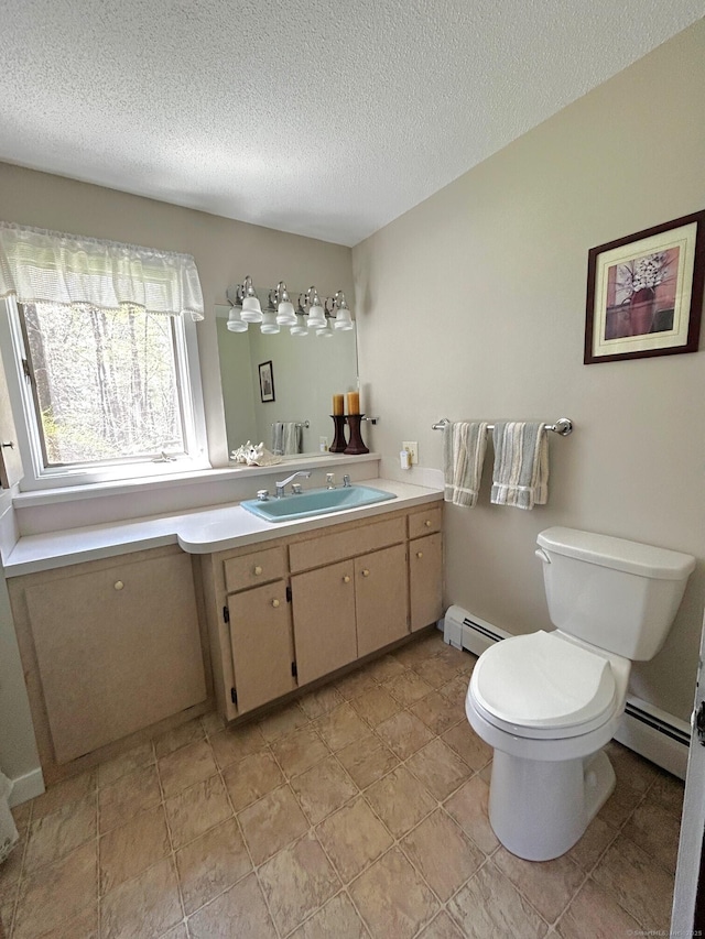 bathroom featuring vanity, a textured ceiling, baseboard heating, and toilet