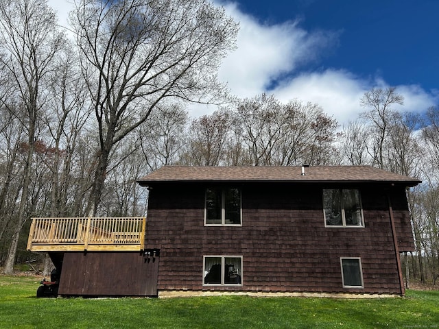 rear view of house with a lawn, a deck, and a shingled roof