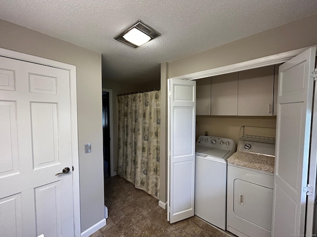 laundry area featuring separate washer and dryer, baseboards, and a textured ceiling