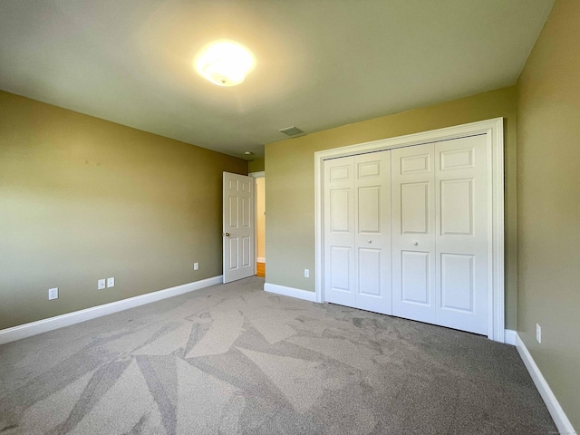 unfurnished bedroom with baseboards, visible vents, a closet, and carpet