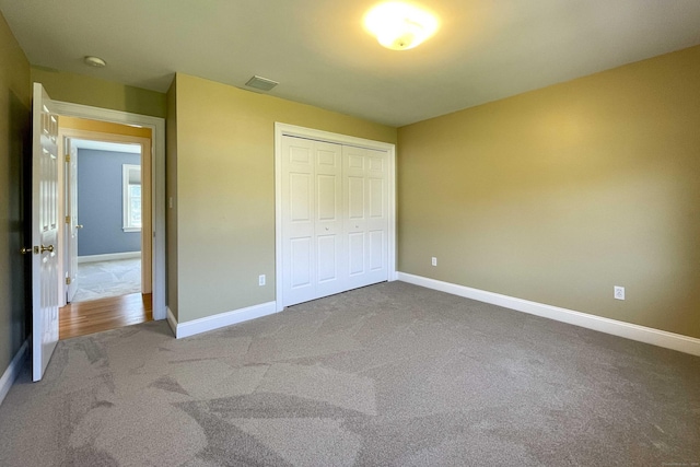 unfurnished bedroom featuring baseboards, visible vents, carpet floors, and a closet
