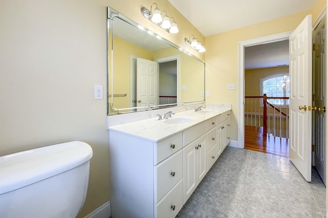 bathroom with a sink, toilet, double vanity, baseboards, and tile patterned flooring