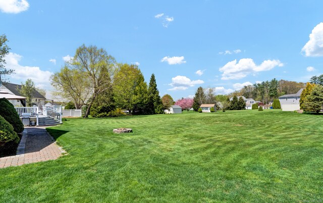 view of yard with an outbuilding, a deck, a fire pit, and a shed