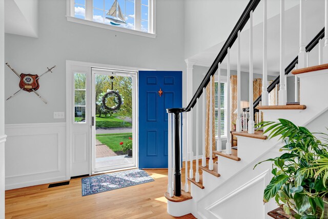 entrance foyer featuring wood finished floors, a high ceiling, visible vents, and stairway