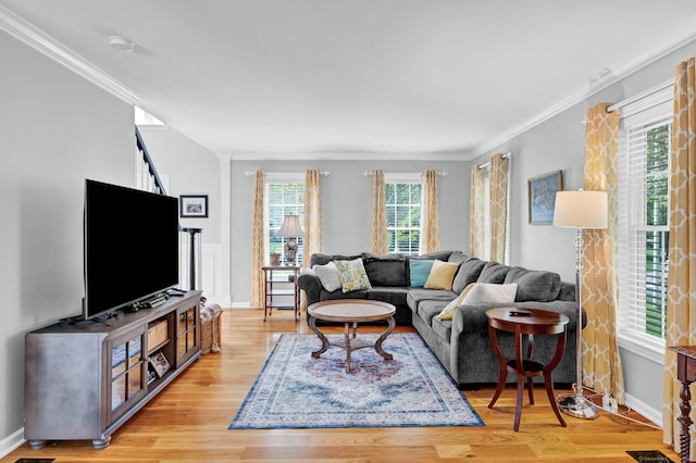 living room featuring crown molding, baseboards, light wood-style floors, and ornate columns