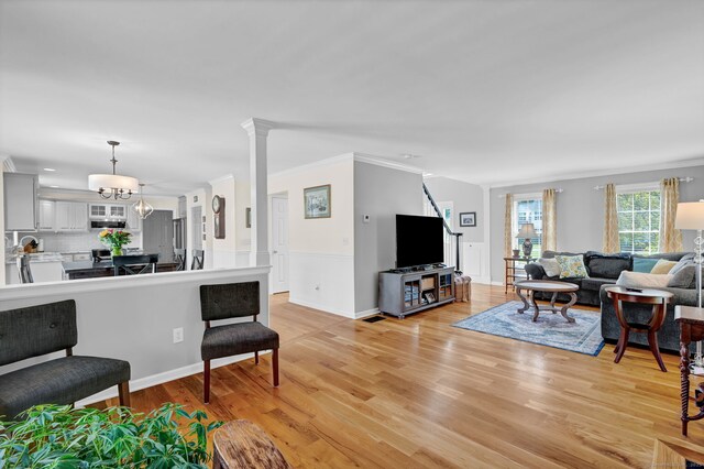 living room featuring crown molding, ornate columns, and light wood-type flooring