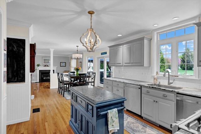 kitchen featuring stainless steel dishwasher, a sink, crown molding, and gray cabinetry