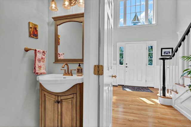 foyer with light wood-style flooring, stairs, and a high ceiling