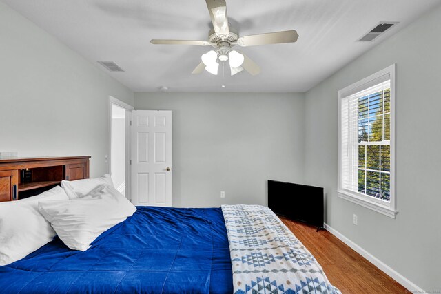 bedroom with visible vents, baseboards, ceiling fan, and wood finished floors