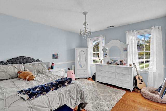 bedroom with a chandelier, visible vents, and light wood-style floors