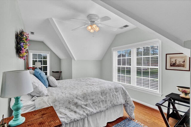 bedroom with visible vents, wood finished floors, vaulted ceiling, and multiple windows