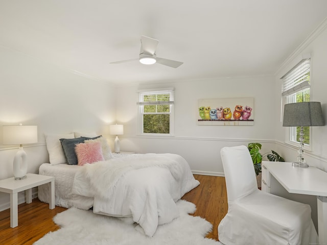 bedroom featuring crown molding, wood finished floors, and multiple windows