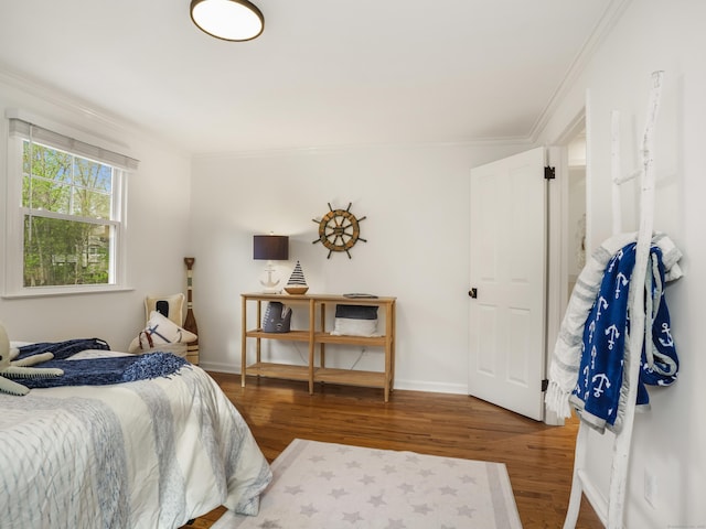 bedroom featuring crown molding, baseboards, and wood finished floors