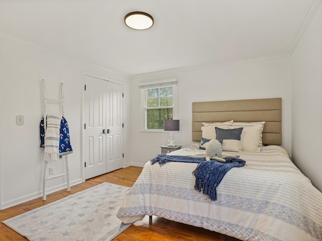 bedroom with baseboards, ornamental molding, a closet, and wood finished floors