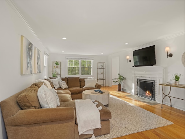 living area featuring crown molding, recessed lighting, wood finished floors, and a fireplace