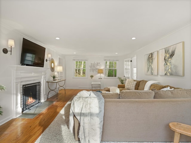 living room with recessed lighting, ornamental molding, a fireplace with flush hearth, and wood finished floors