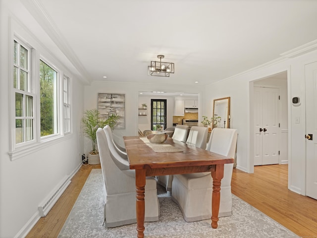 dining room featuring crown molding, an inviting chandelier, light wood-style floors, baseboards, and a baseboard heating unit