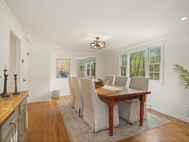dining space with baseboards, an inviting chandelier, ornamental molding, and light wood-type flooring