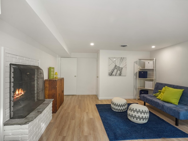 living room featuring visible vents, a brick fireplace, baseboards, light wood-style floors, and recessed lighting