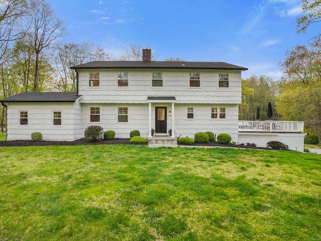 view of front of home featuring a shingled roof, a front yard, and a chimney