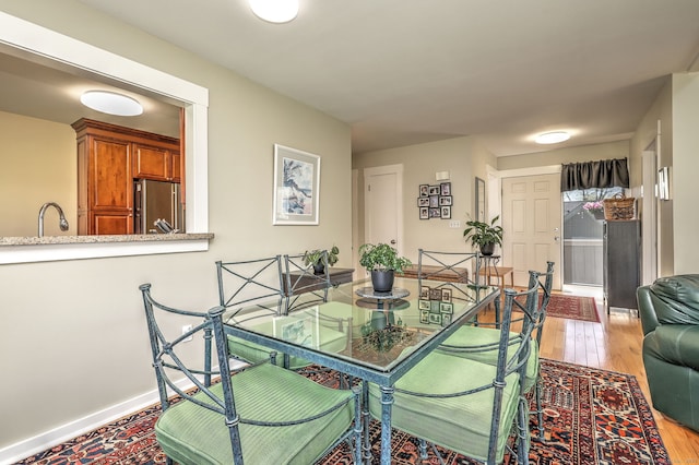 dining area featuring baseboards and light wood-style flooring
