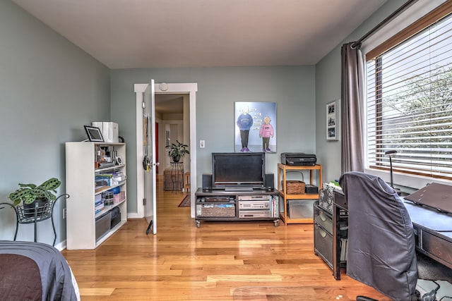 office area featuring baseboards, light wood finished floors, and a healthy amount of sunlight