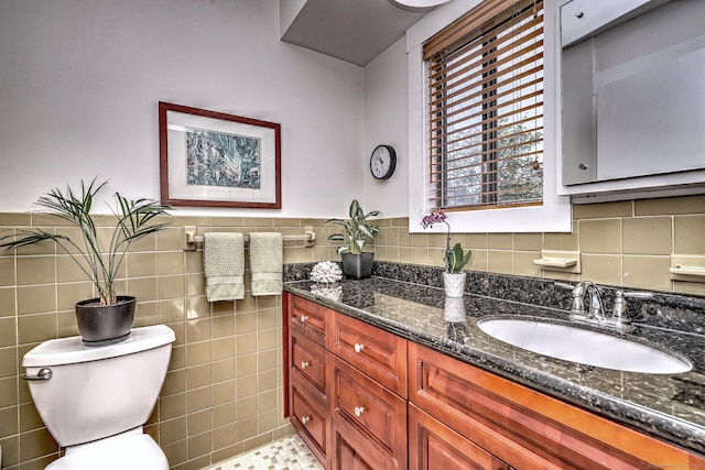bathroom with toilet, tile walls, a wainscoted wall, and vanity