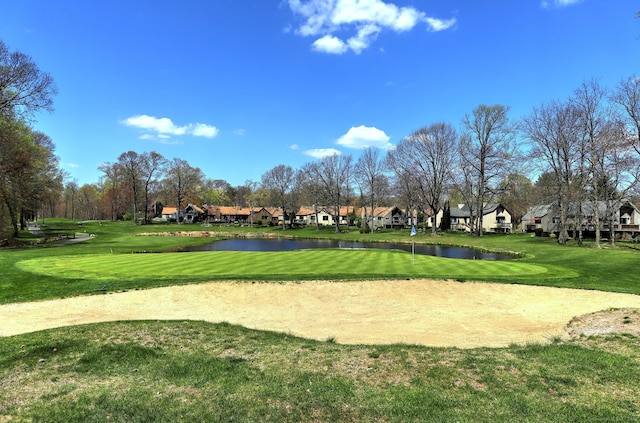 view of home's community with a water view, view of golf course, a yard, and a residential view
