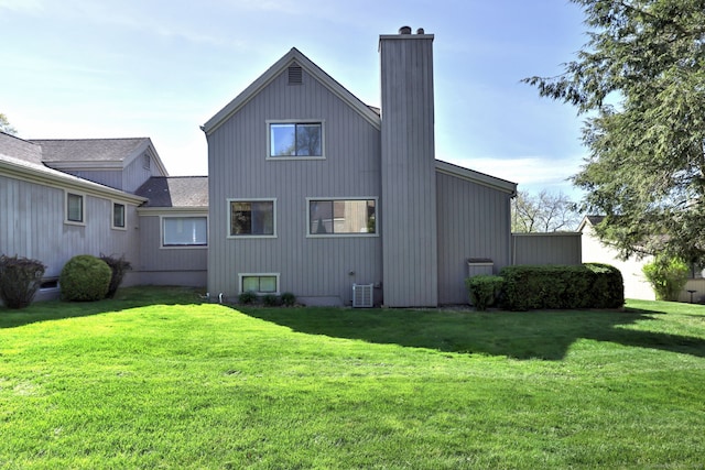 rear view of property featuring a yard, a chimney, and central AC unit