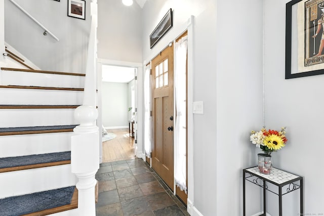 entrance foyer with baseboards, stone tile floors, and stairs