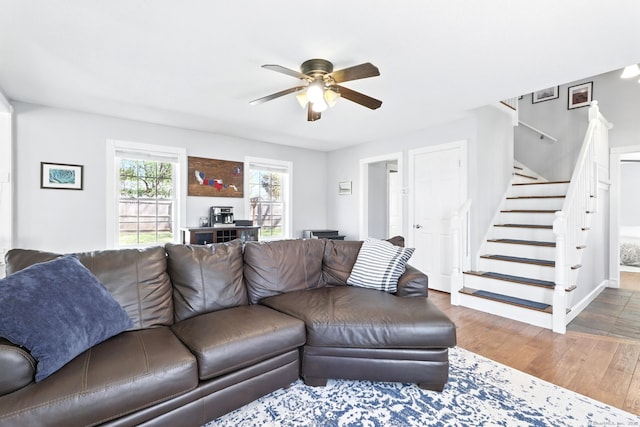 living room featuring baseboards, ceiling fan, wood finished floors, and stairway