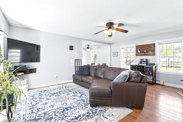 living area featuring baseboards, ceiling fan, a healthy amount of sunlight, and a baseboard radiator