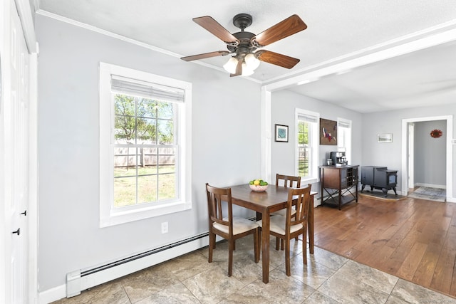 dining room featuring baseboards, baseboard heating, a ceiling fan, and a wealth of natural light
