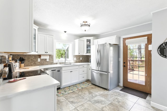 kitchen featuring appliances with stainless steel finishes, tasteful backsplash, a sink, light countertops, and glass insert cabinets