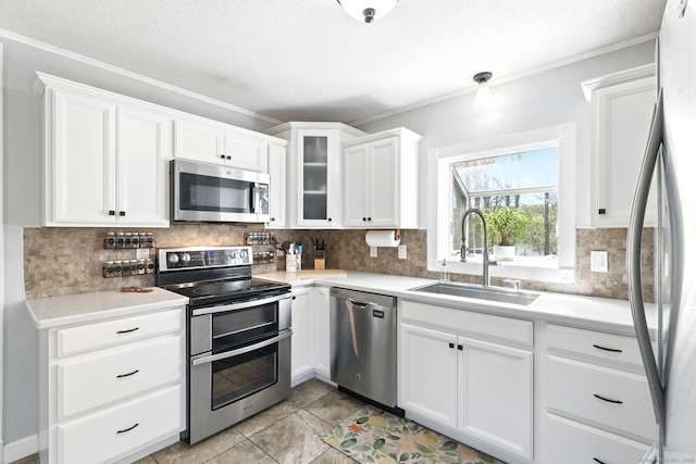 kitchen with crown molding, light countertops, white cabinetry, a sink, and stainless steel appliances