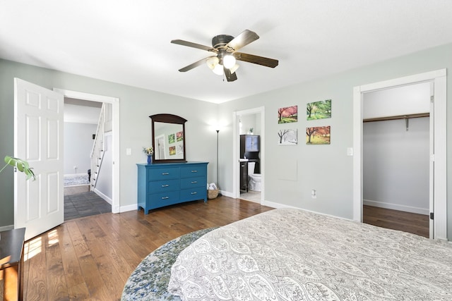 bedroom featuring a spacious closet, baseboards, ensuite bath, and dark wood-type flooring