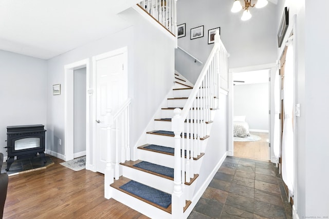stairway featuring baseboards, a wood stove, and stone tile flooring