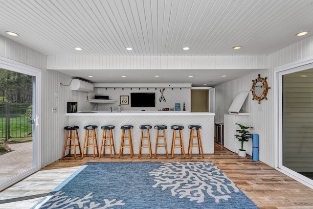 kitchen featuring wood finished floors, a breakfast bar, a wall mounted AC, wooden ceiling, and recessed lighting