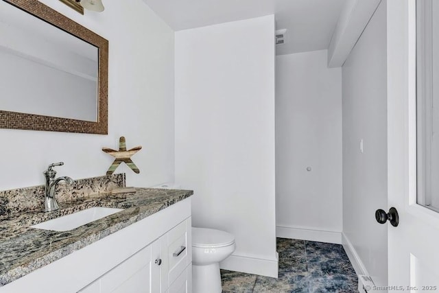 bathroom with toilet, vanity, and baseboards