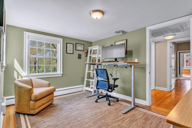 office space with baseboard heating, wood finished floors, and baseboards