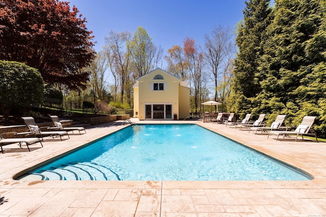 view of swimming pool with a patio area, an outbuilding, fence, and a storage structure