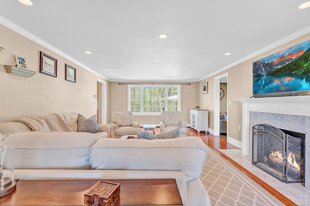 living room with ornamental molding, wood finished floors, a fireplace, recessed lighting, and baseboards