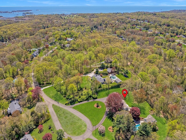 aerial view of property and surrounding area with a heavily wooded area and a large body of water