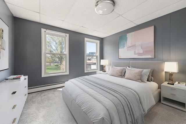 carpeted bedroom with a paneled ceiling and a baseboard radiator
