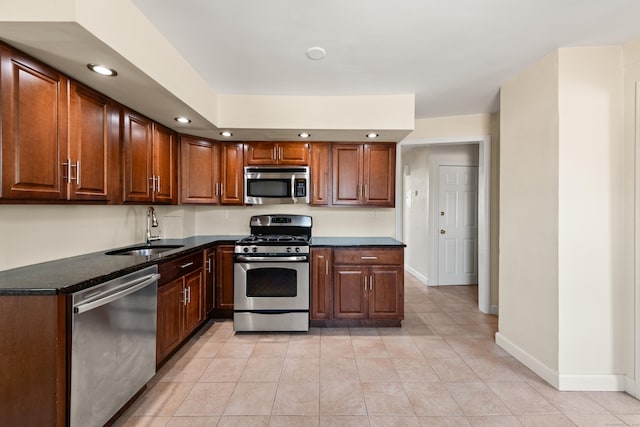 kitchen featuring appliances with stainless steel finishes, baseboards, light tile patterned floors, and a sink