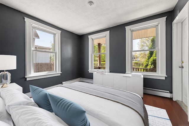 bedroom featuring a textured ceiling, dark wood-type flooring, and a baseboard radiator