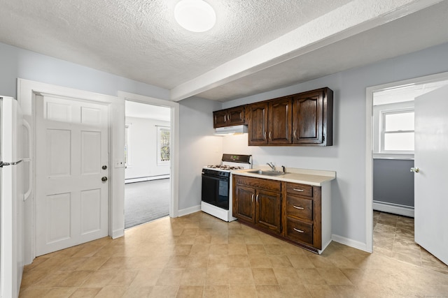 kitchen with a sink, a baseboard heating unit, freestanding refrigerator, under cabinet range hood, and gas range